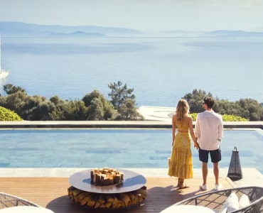 Couple enjoying a scenic view by the pool overlooking a lake and mountains.