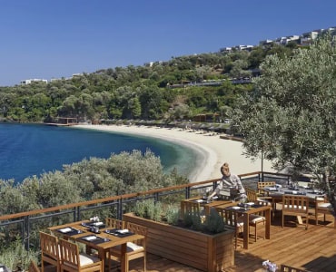 Coastal beach view with outdoor dining under clear skies.