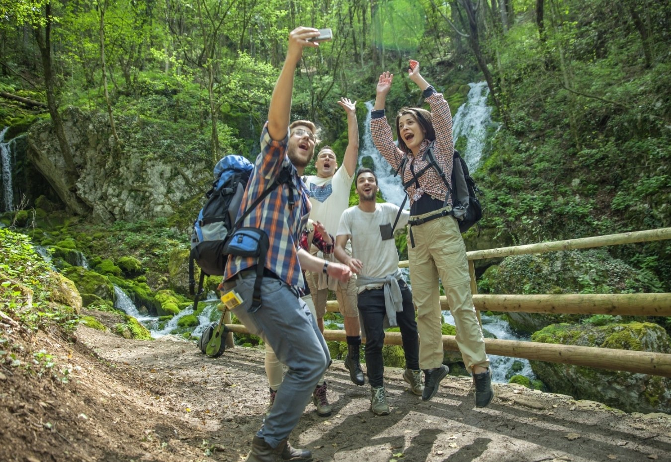 Friends hiking and celebrating in a forest with backpacks and maps.