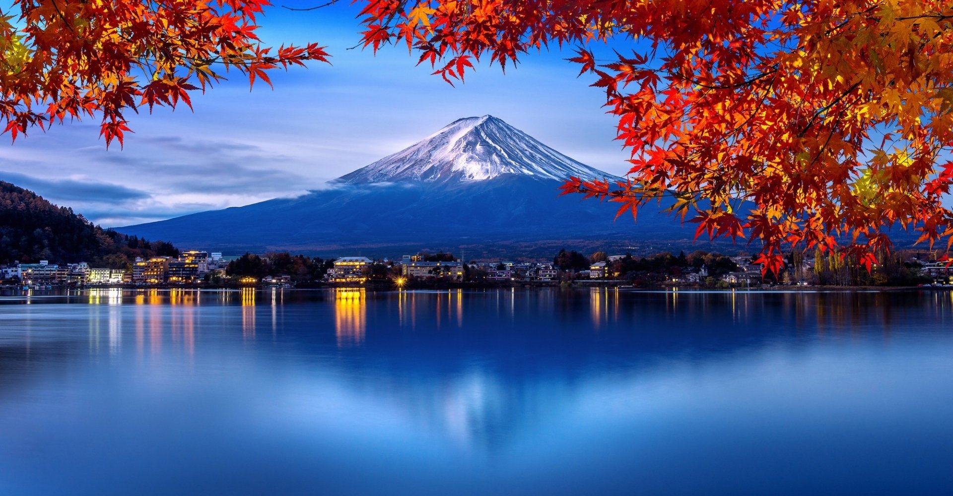 Mount Fuji with autumn leaves reflected in calm water.